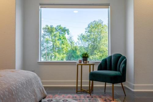 a bedroom with a green chair and a window at Cute Cozy house close to major sporting events and restaurants in Houston