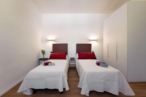 Cette chambre comprend 2 lits avec des murs blancs et des oreillers rouges. dans l'établissement Comfort Apartment Panicale, à Florence