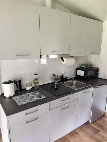 a kitchen with white cabinets and a sink at domki przy lipowej 14 in Łuka