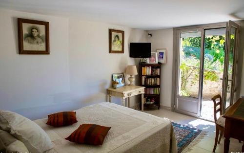 a bedroom with a bed and a table and a window at Le Mas Dauphinois in Le Grand-Lemps
