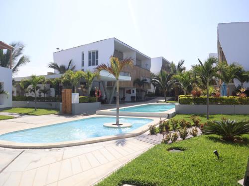 a villa with a swimming pool and palm trees at Deplaya Zorritos-Tumbes in Bocapán