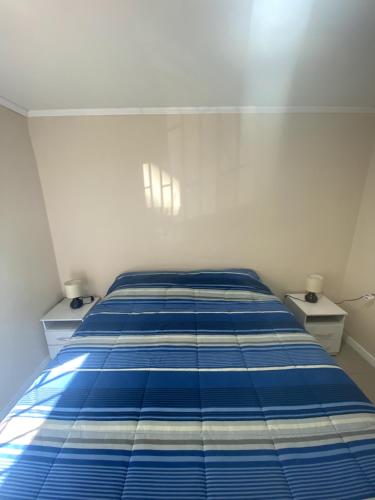 a blue bed in a room with two night stands at Departamento primer piso cercano a Alameda in Constitución