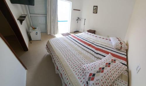 a bedroom with a bed with a quilt on it at Pousada Sol da Manhã in Guarujá