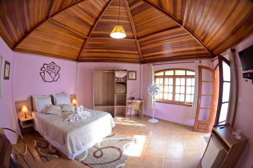 a bedroom with a large bed with a wooden ceiling at Pousada Villa Da Montanha in São Bento do Sapucaí
