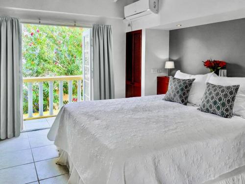 a bedroom with a white bed and a balcony at Villa La Pura Vista in Kralendijk