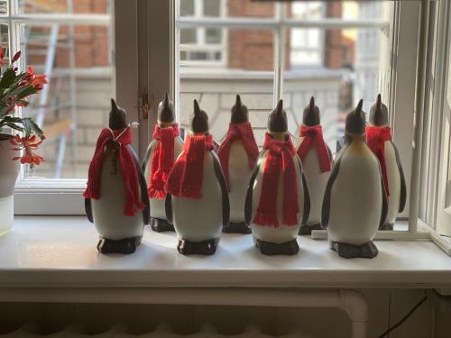 a group of penguins dressed in christmas costumes sitting on a window sill at Camillas Holiday home Copenhagen City Centre in Copenhagen