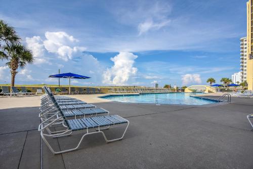 a pool with two lounge chairs and a blue umbrella at Phoenix 6 Unit 1015 in Orange Beach