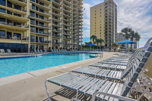 a swimming pool with lounge chairs in front of a building at Phoenix 6 Unit 1015 in Orange Beach