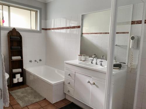 a white bathroom with a tub and a sink at Superb Villa in Beach Resort in Coffs Harbour