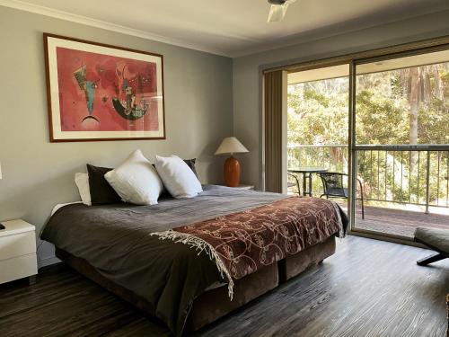 um quarto com uma cama grande e uma janela grande em Superb Villa in Beach Resort em Coffs Harbour