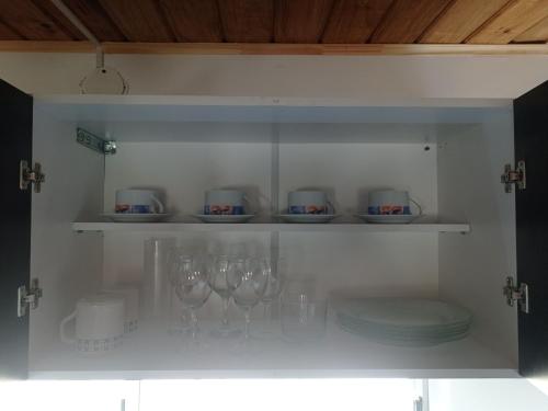 a cupboard with wine glasses and plates in it at Cabañas alpinas alumine in Perito Moreno