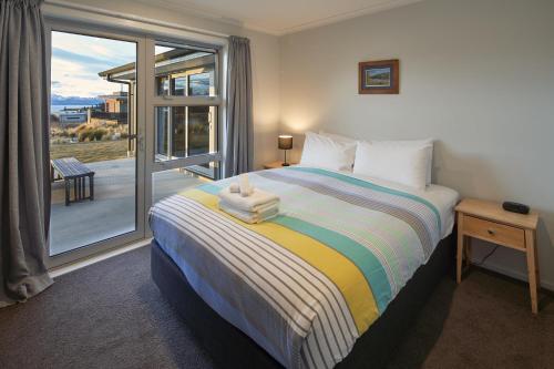 a bedroom with a bed with a view of a balcony at Majestic View - Lake Tekapo in Lake Tekapo