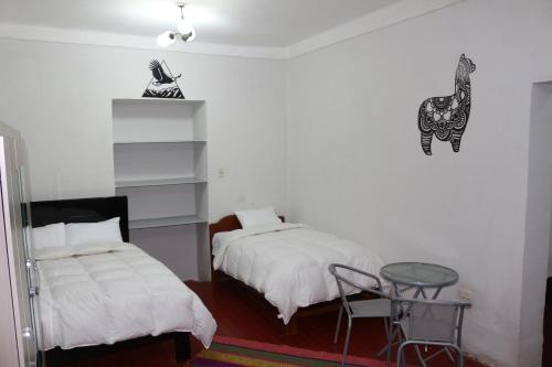 a bedroom with two beds and a glass table at Apartamento Privado en Centro Histórico de Cusco in Cusco