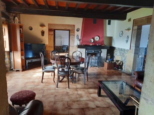 a living room with a table and chairs and a tv at Palacio Marqués Vega de Anzo - Villa de campo sXVII in Siero