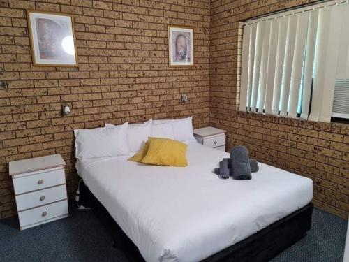 a bedroom with a large white bed and a brick wall at Motel Wellington Wodonga in Wodonga