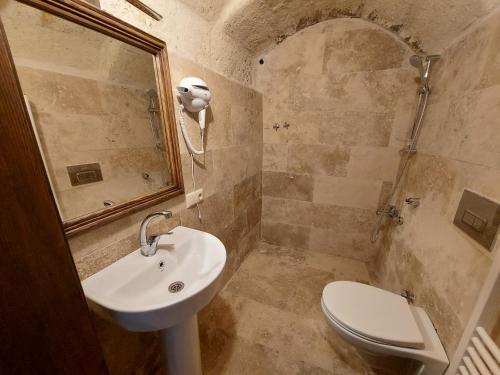 a bathroom with a sink and a toilet and a mirror at ARMEsos Cave Hotel in Urgup