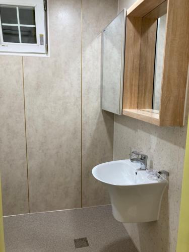 a bathroom with a sink and a shower at Namhae Frankfurt Pension in Namhae