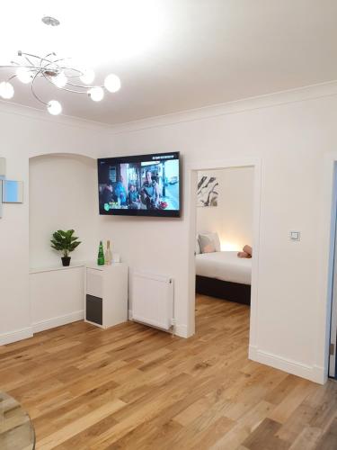 a living room with a bed and a flat screen tv on the wall at Glasgow Comfortable and Modern 3 Bedroom Mid Terraced Villa in Glasgow