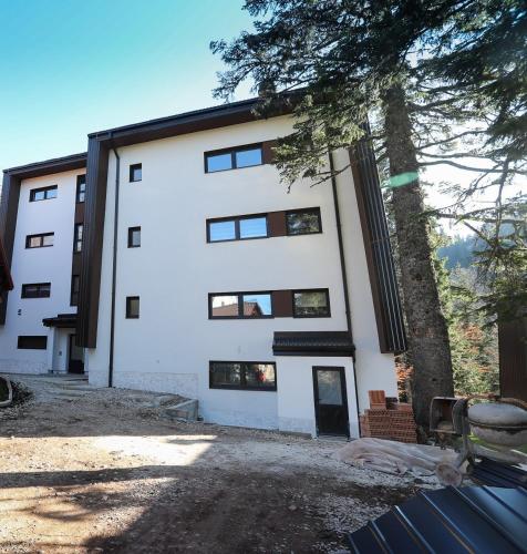 a white building with a tree in front of it at Apartman 5 plus - Vila Nova in Jahorina
