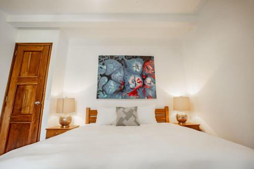 a bedroom with a white bed and a painting on the wall at Playa Venao Hotel Resort in Playa Venao
