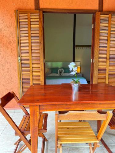 a wooden table with two chairs and a table with flowers on it at Chalé das Águas in Igaratá