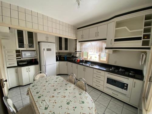 a kitchen with a table and chairs and a white refrigerator at Quarto Residencial320 - Timbó in Timbó