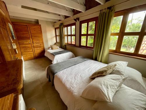 a bedroom with two beds in a room with windows at Hotel El Manglar in Playa Grande