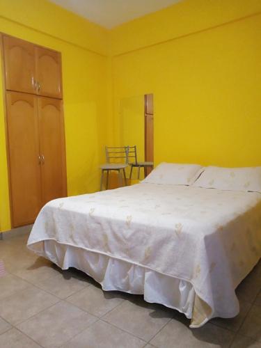 1 dormitorio con 1 cama blanca en una pared amarilla en Departamento Monoambiente FRANLUC en Colón