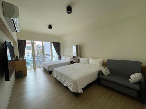 una camera d'albergo con due letti e un divano di 墾丁星院旅宿 a Kenting