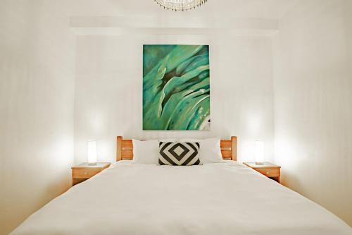 a bedroom with a white bed with a painting on the wall at Playa Venao Hotel Resort in Playa Venao