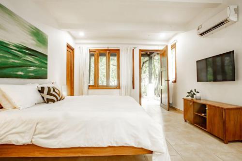 a bedroom with a white bed and a painting on the wall at Playa Venao Hotel Resort in Playa Venao