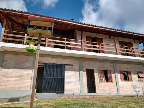 a house with a balcony on top of it at Casa Recanto Beija Flor, Monte Verde in Monte Verde