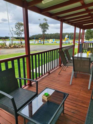 a porch with chairs and a table and a playground at Stoney Park Holiday Park in Telegraph Point