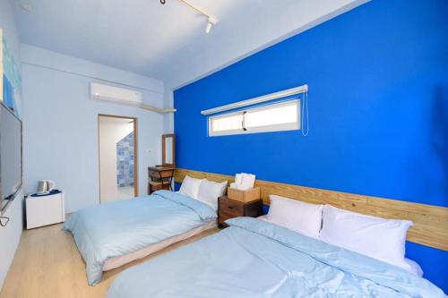 a blue room with two beds and a blue wall at 夏天民宿 in Magong