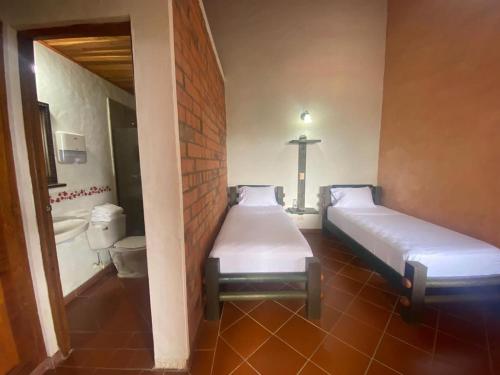 two beds in a room with a cross on the wall at Granja del Cafe Hotel y Centro de convenciones in Venecia
