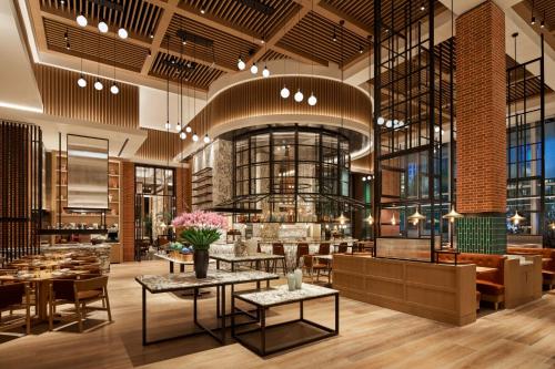 a lobby of a restaurant with tables and chairs at Shangri-La Qiantan, Shanghai - Steps away from the Oriental Sports Center, and easy reach the vibrant art scene of West Bund in Shanghai
