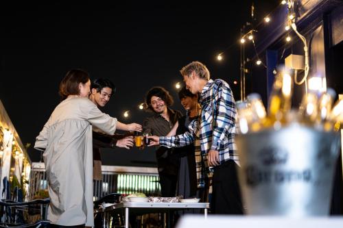 Un gruppo di persone che si aggirano intorno a un uomo con un drink in mano di Hotel S-Presso Central ad Osaka