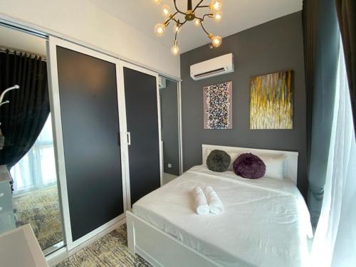 a bedroom with a white bed and a chandelier at Triple D @ Troika Residence in Kota Bharu