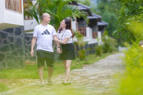 a man and a woman walking down a dirt road at Mai Chau Mountain View Resort in Mai Chau