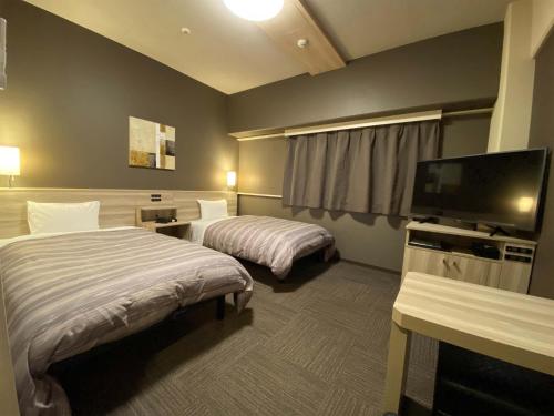松江市にあるホテル ルートイン 松江のベッド2台、薄型テレビが備わるホテルルームです。