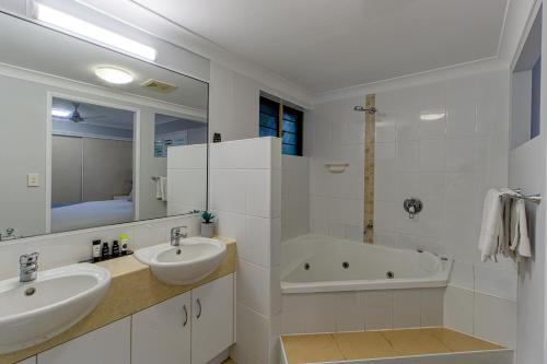 a white bathroom with two sinks and a bath tub at Townsville Southbank Apartments in Townsville