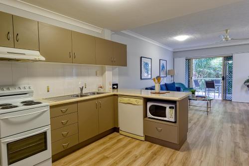 a kitchen with white appliances and a living room at Townsville Southbank Apartments in Townsville