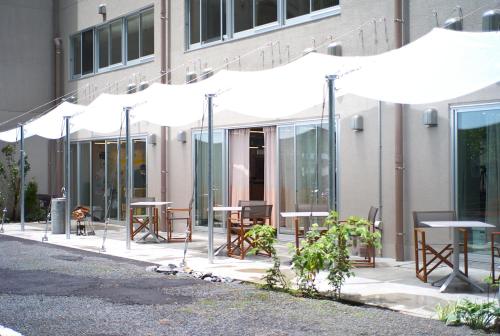 a group of tables and umbrellas in front of a building at TAKAONE ACTIVITY＆STAY in Hachioji