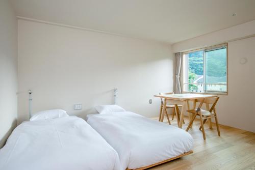 two beds in a room with a table and a window at TAKAONE ACTIVITY＆STAY in Hachioji