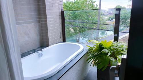 a bathroom with a tub and a window with a plant at 川岸空中villa in Luodong
