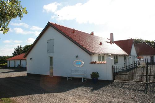 ein weißes Gebäude mit rotem Dach und einem Zaun in der Unterkunft Sov Godt i Arnborg Bed & Breakfast in Arnborg