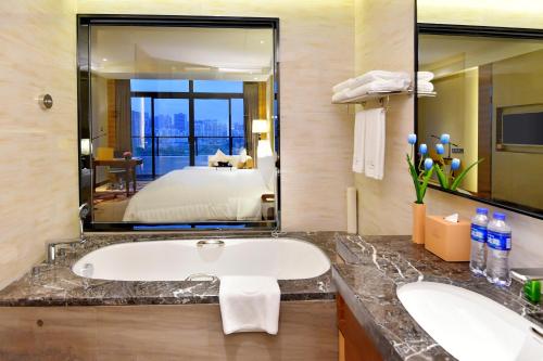 a bathroom with a tub and a large mirror at Grand Skylight International Hotel Huizhou in Huizhou