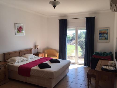 ein Schlafzimmer mit einem Bett und einem großen Fenster in der Unterkunft Villa Castelos, Quelfes, Eastern Algarve private pool in Olhão