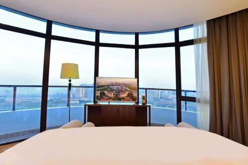 a bedroom with a large bed and large windows at Grand Skylight International Hotel Huizhou in Huizhou