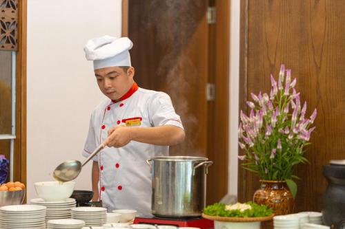 a man in a kitchen preparing food with a spoon at Mai Chau Mountain View Resort in Mai Chau